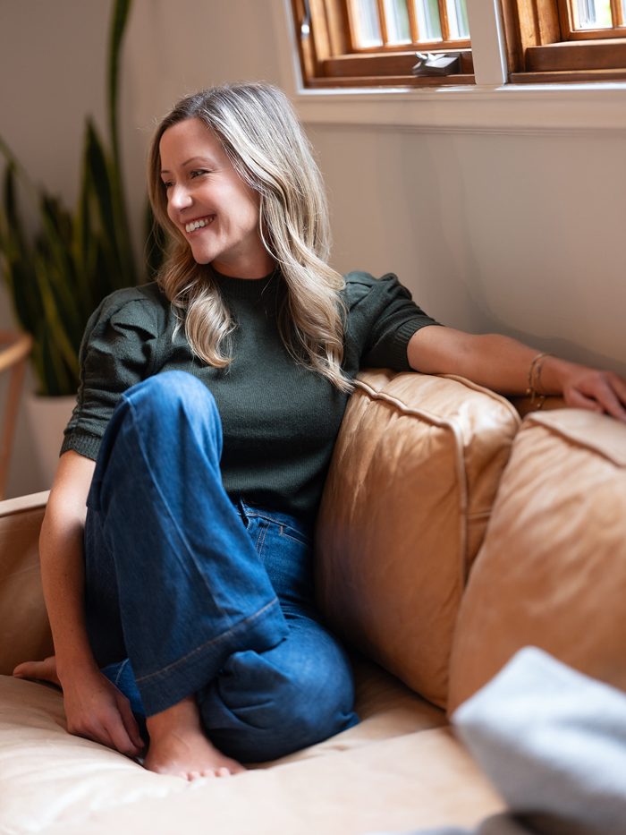 Jen laughing on her sofa